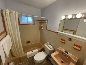 A bathroom with a bathtub, toilet, sink, and a mirror with lights. - RusMar Motel (Wildwood)