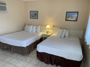 A hotel room with two beds, a nightstand with a lamp, and two framed pictures on the wall. - RusMar Motel (Wildwood)