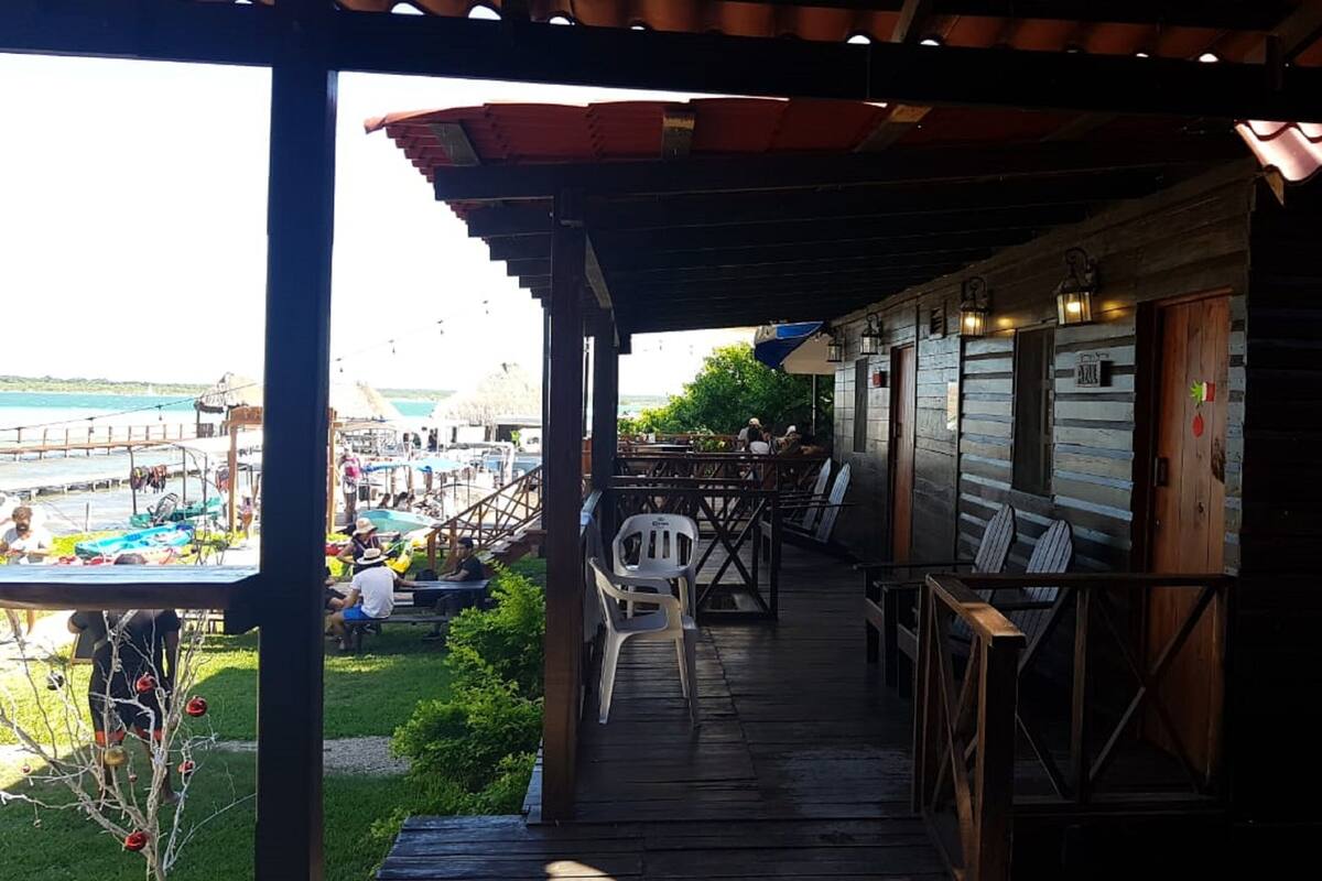 Une terrasse en bois avec des sièges extérieurs, donnant sur une marina où sont amarrés des bateaux, et offrant une vue dégagée sur l’eau.
