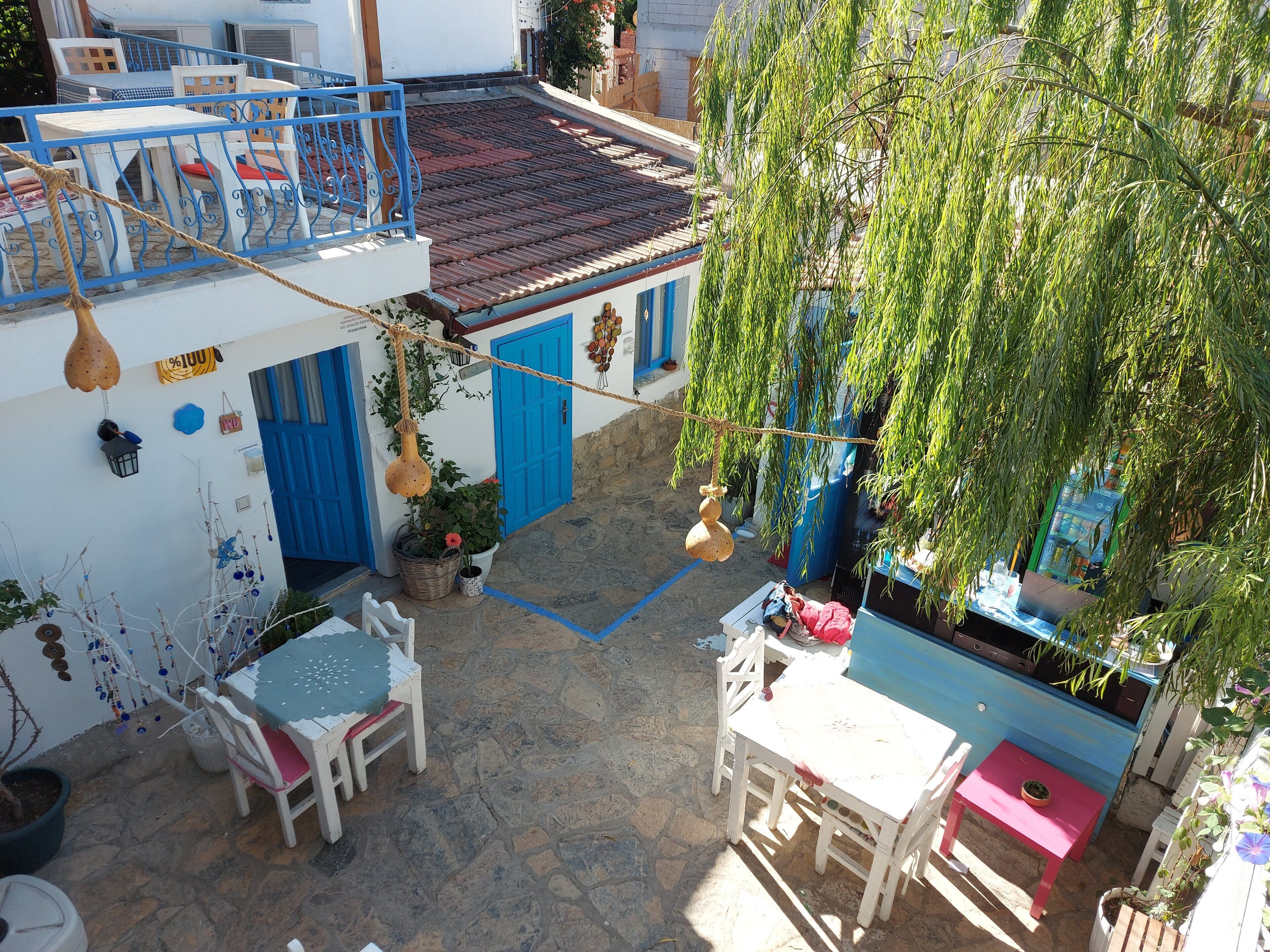 A courtyard with a stone floor, white and blue furniture, and a hanging rope.