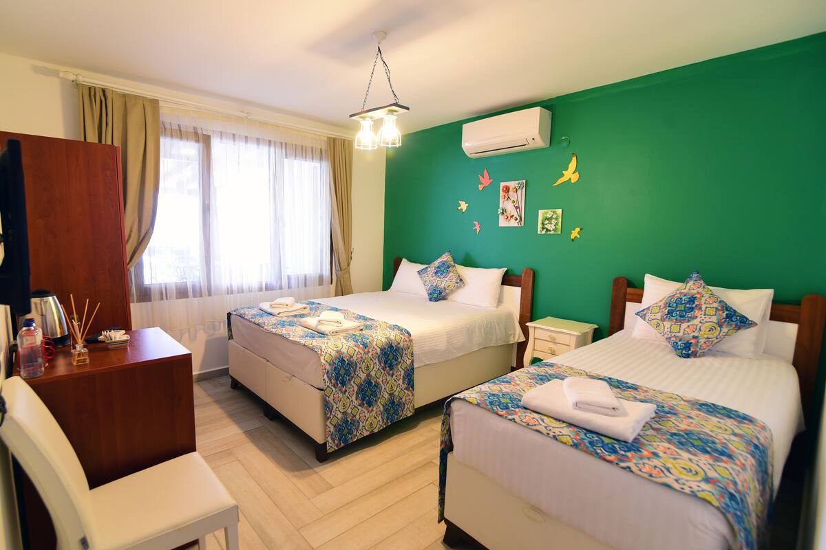 A hotel room with two beds, a desk, a chair, and a window with curtains.