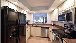 A modern kitchen with stainless steel appliances, white cabinetry, and a tiled floor. - Shorewalk "A Little Piece of Paradise" close to beaches, golf, restaurants, IMG (Bradenton)