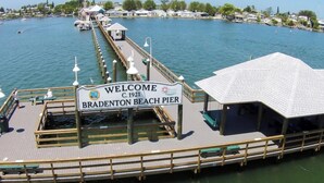 A pier with a sign reading "Welcome C.1921 Bradenton Beach Pier" and a boat docked at the end. - Shorewalk "A Little Piece of Paradise" close to beaches, golf, restaurants, IMG (Bradenton)