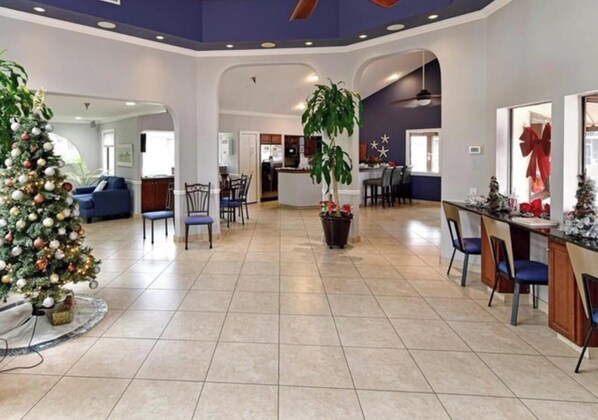 A spacious lobby with a Christmas tree, a large potted plant, and a bar area.