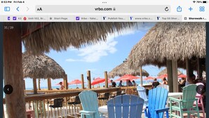 A beachside restaurant with outdoor seating and thatched umbrellas. - Shorewalk "A Little Piece of Paradise" close to beaches, golf, restaurants, IMG (Bradenton)