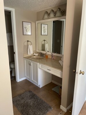 A bathroom with a double sink, a large mirror, and a toilet. There are towels hanging on the wall and a rug on the floor. - Shorewalk "A Little Piece of Paradise" close to beaches, golf, restaurants, IMG (Bradenton)