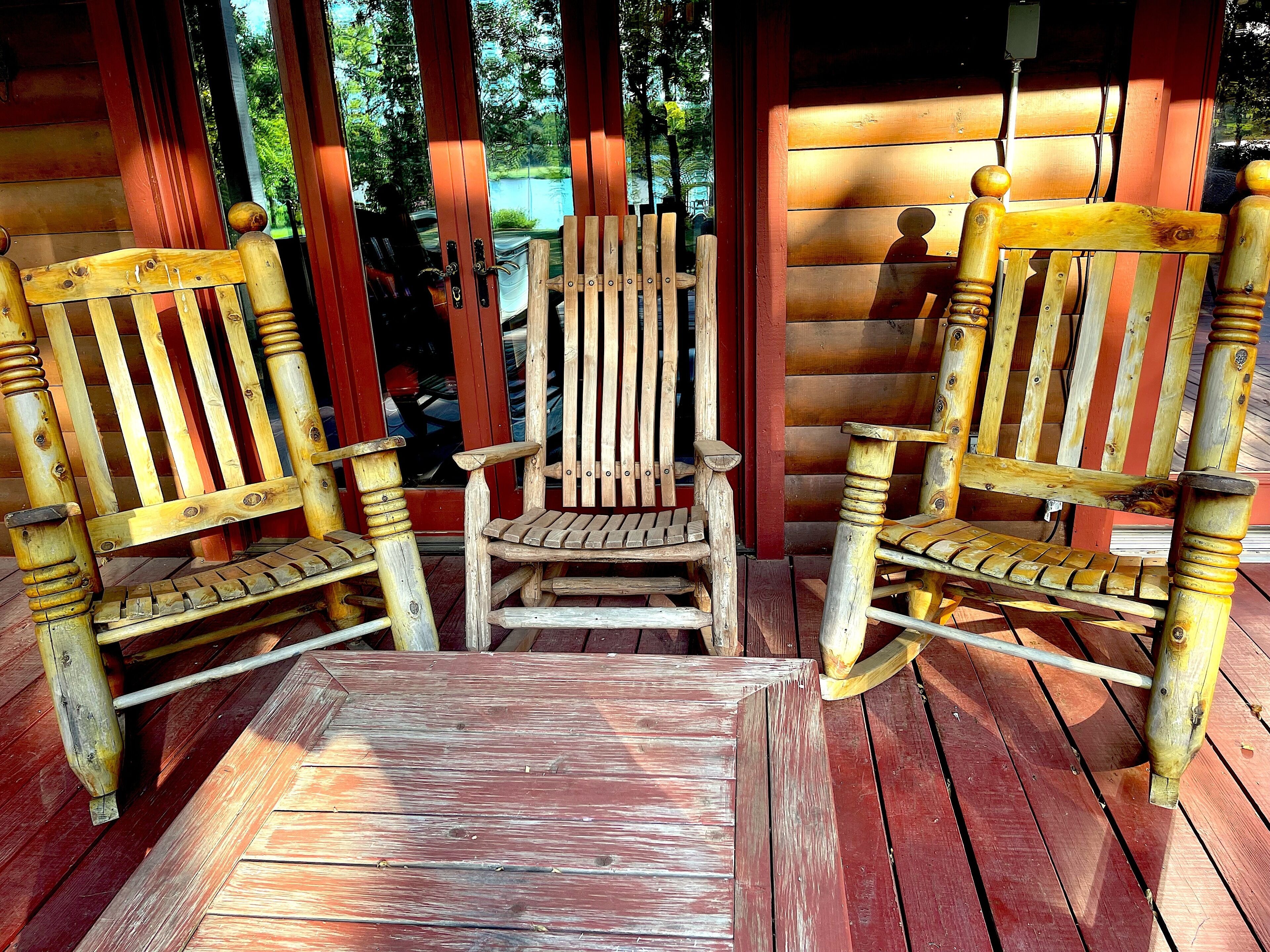 Une terrasse en bois avec deux fauteuils à bascule et une petite table.