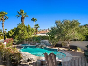 A swimming pool with a tiled edge, surrounded by palm trees and cacti, with a view of a mountain in the background. - Newly Renovated Palm Springs Oasis (Palm Springs)