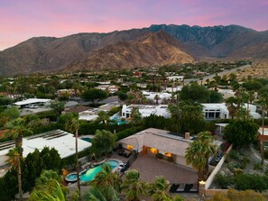 A residential area with a large mountain in the background, houses with solar panels, and a swimming pool.