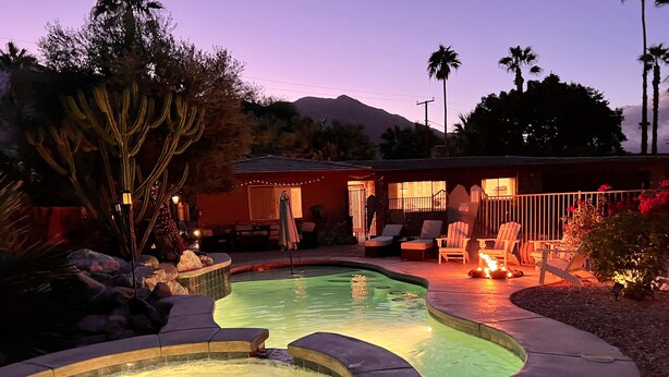 Une piscine avec un jacuzzi, entourée de chaises longues et d’un espace patio avec une vue imprenable sur les montagnes.