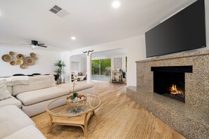 A modern living room with a sofa, coffee table, fireplace, and a TV mounted on the wall. - Newly Renovated Palm Springs Oasis (Palm Springs)