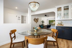 Une cuisine moderne avec une table ronde en verre, des chaises en bois et un lustre.
