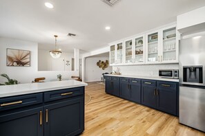 A modern kitchen with a central island, dark cabinetry, and a stainless steel refrigerator.