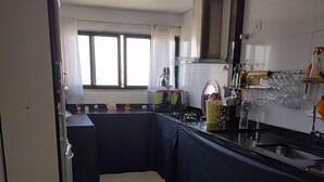 Una cocina con estufa a gas, lavabo y ventana con cortinas.