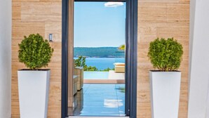 A hotel entrance with a view of a pool and a body of water.