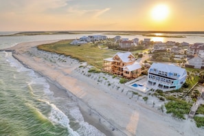 A coastal residential area with beachfront properties, including a house with a swimming pool and another with a large porch.