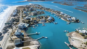 Vue aérienne d’une zone résidentielle côtière, avec des maisons, des quais et une plage.