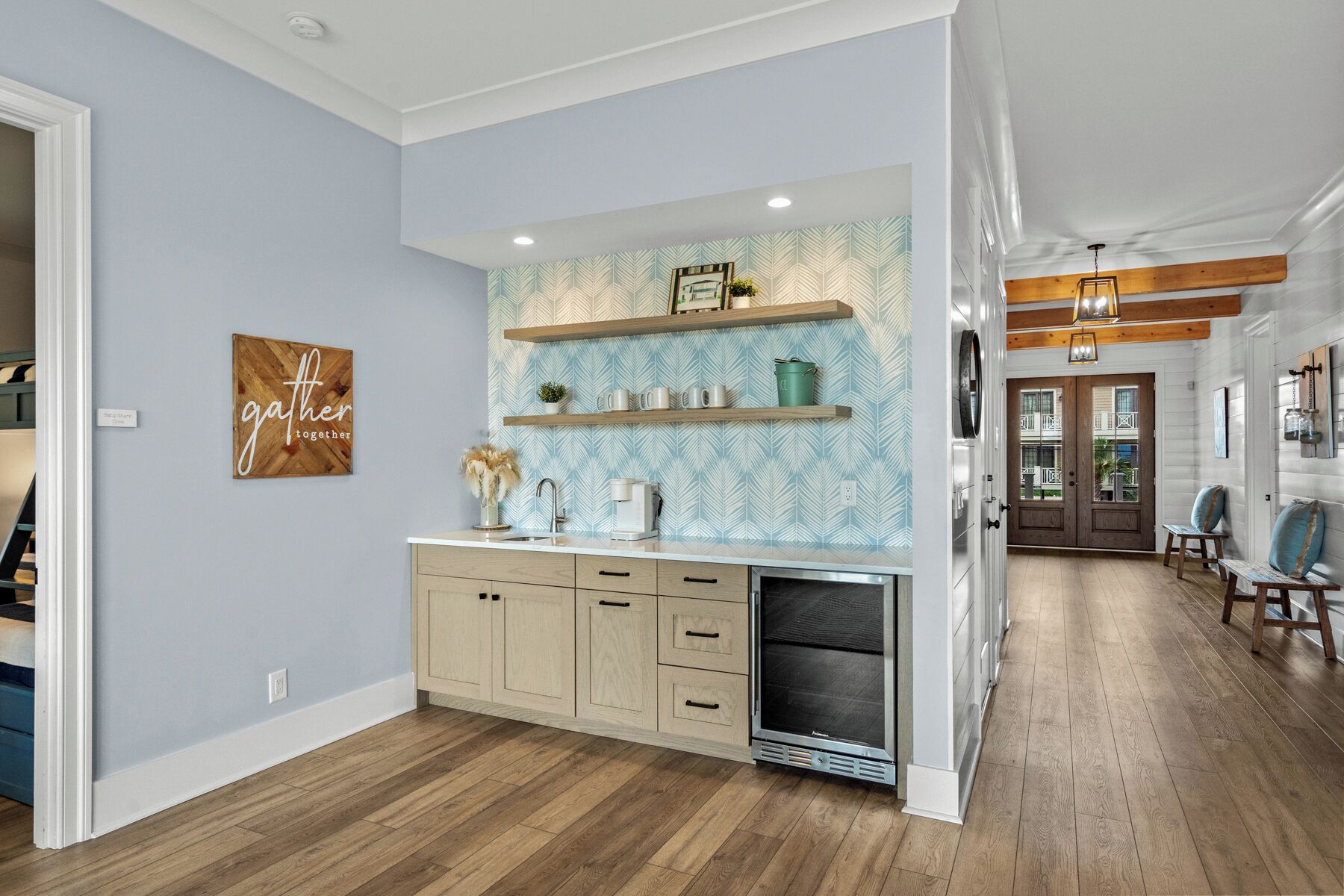 A kitchen with light blue walls, wooden cabinets, and a built-in microwave. There are shelves above the sink and a decorative sign on the wall.