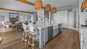 Une cuisine moderne dotée d’un grand îlot central, de meubles blancs et d’un plancher en bois.