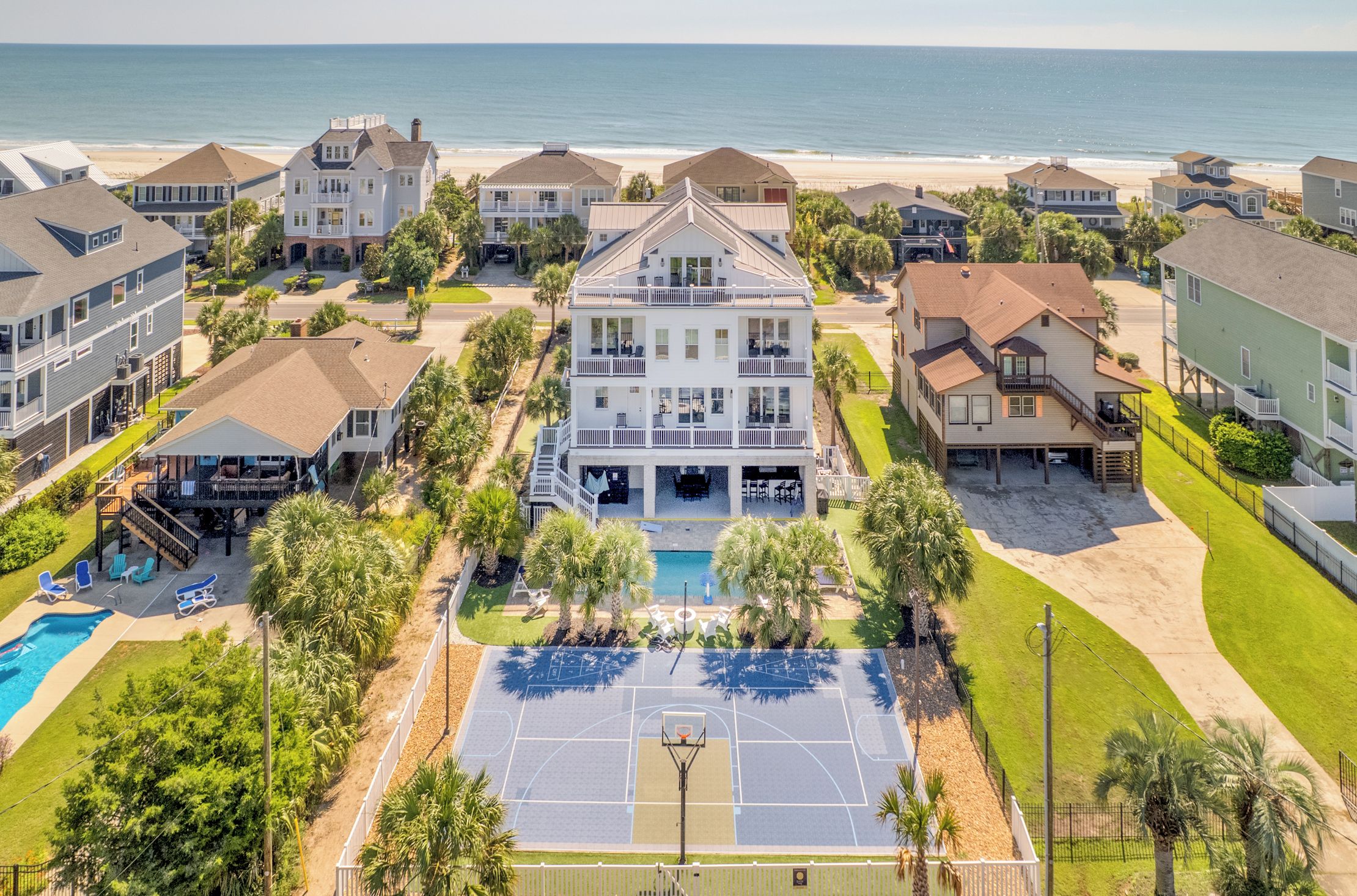 A residential area with a large house featuring a pool and a basketball court.