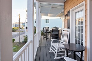A wooden deck with a table and chairs, overlooking a street.