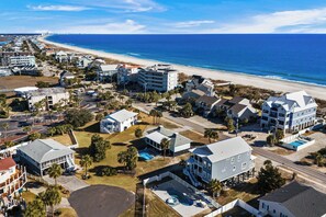 Vista aérea de una zona residencial costera con casas, una playa y un cielo azul despejado.