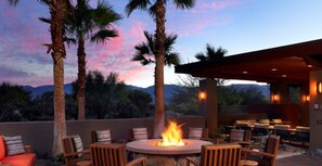 Relax by the fire pit in a serene outdoor setting surrounded by palm trees and distant mountains.