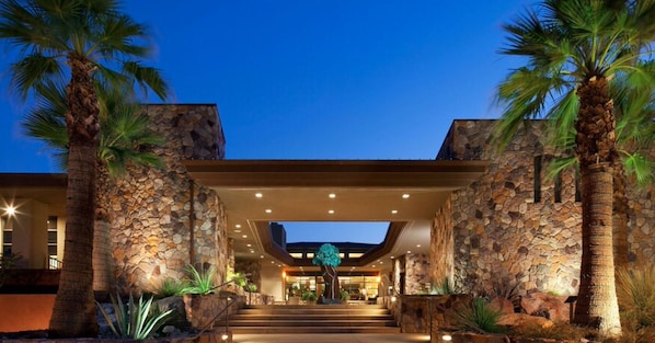 Welcome to our hotel, where a grand staircase leads up to the main building, surrounded by lush palm trees.