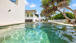 Relax by the serene pool surrounded by lush greenery and a staircase leading to an upper level.