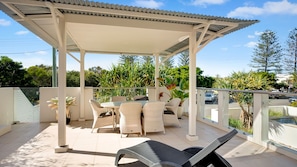 Relax in a serene outdoor space with a covered seating area, lounge chairs, and a table.