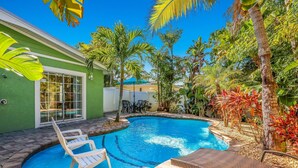 A swimming pool surrounded by tropical plants and outdoor furniture. - Key Lime Cottage by Beach Boutique Rentals (Holmes Beach)
