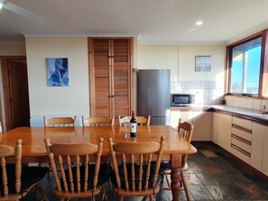 A dining area with a wooden table and chairs, a refrigerator, a microwave, and a window with a view.