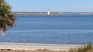 A lighthouse on a small island in a calm body of water. - The Blue Heron Hideaway (Tybee Island)