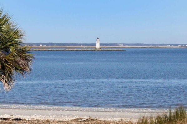 A lighthouse on a small island in a calm body of water.