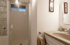 Un baño con ducha, lavabo y espejo.