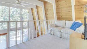 A cozy room with a wooden ceiling, a white sofa, and a ceiling fan.