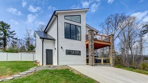 Een modern huis met twee verdiepingen, een stenen pilaar en een balkon.
