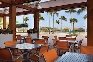 Relax in a shaded outdoor space with a pergola, metal tables, and comfortable seating.