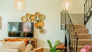 Un saló amb televisió plana, una planta de cactus, un telèfon antic i una escala.