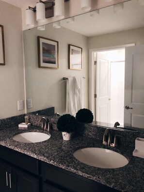 A bathroom with two sinks, a mirror, and a door.
