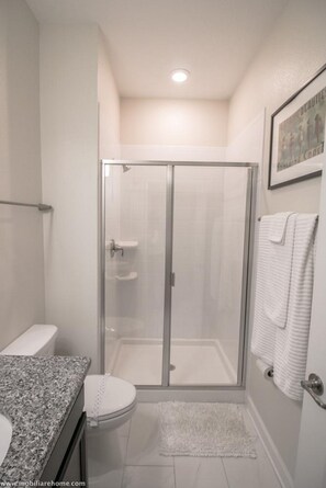 Une salle de bain avec une douche à parois de verre, des toilettes et un lavabo.