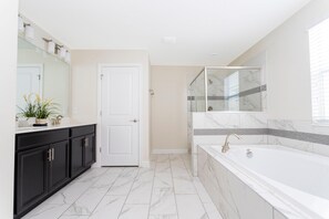 A modern bathroom with a white bathtub, black cabinets, and a glass shower enclosure. - 1520 FD 6BR Luxury Villa Pool Game Room (Davenport)