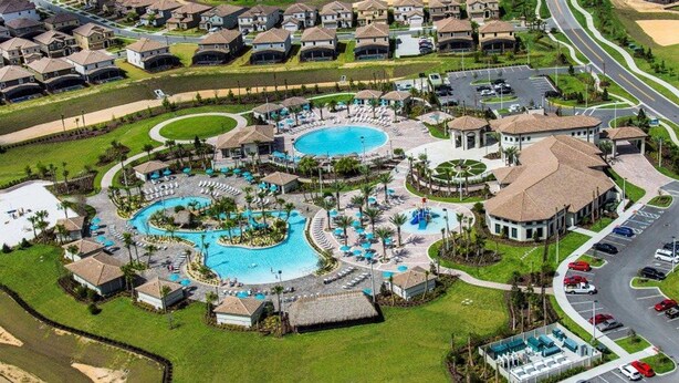 Luchtbeeld van een resort met meerdere zwembaden, een golfbaan en een parkeerplaats.