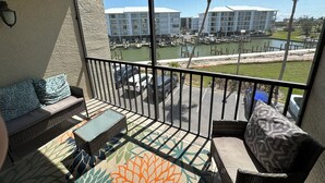 A balcony with a view of a marina, a pool, and a building complex.