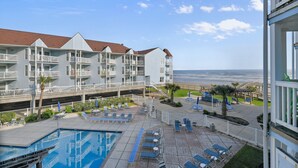 A hotel with a pool, lounge chairs, and a view of the ocean. - Seascape 1215 in Galveston (Galveston)