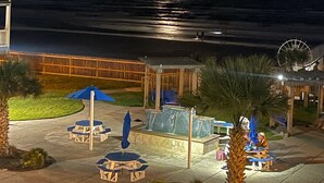 A beachfront resort with outdoor seating, a Ferris wheel, and a view of the ocean. - Seascape 1215 in Galveston (Galveston)