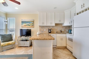 Modern kitchen with appliances, granite countertop, and a television.