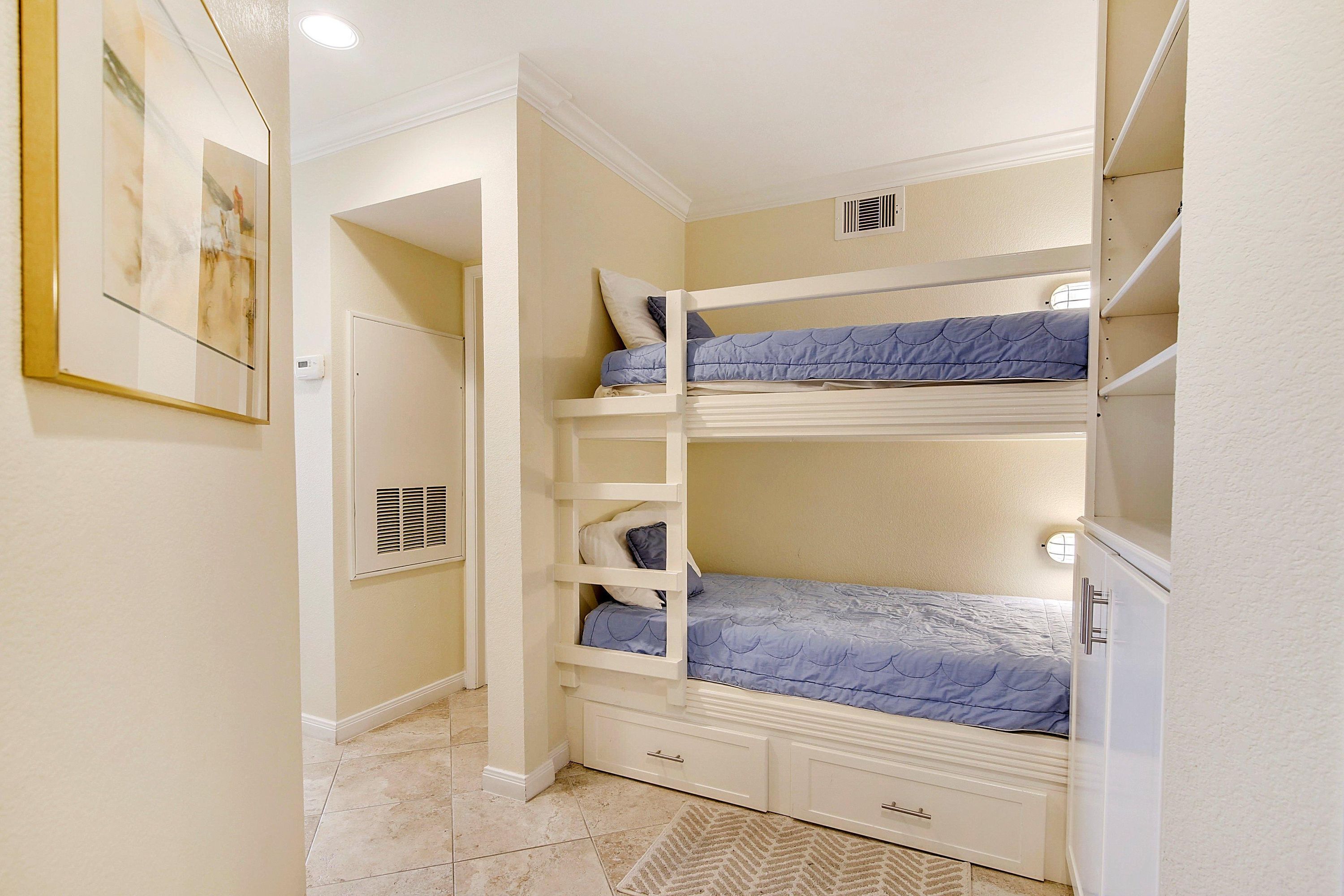 A bunk bed room with a white door, a vent, and a small storage drawer.