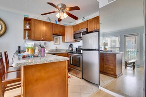 A kitchen with wooden cabinets, stainless steel appliances, a central island, and a ceiling fan.