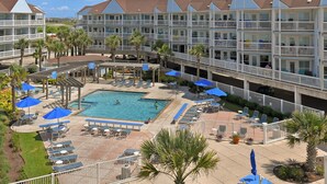 A hotel with a pool area, outdoor seating, and a view of the surrounding landscape.
